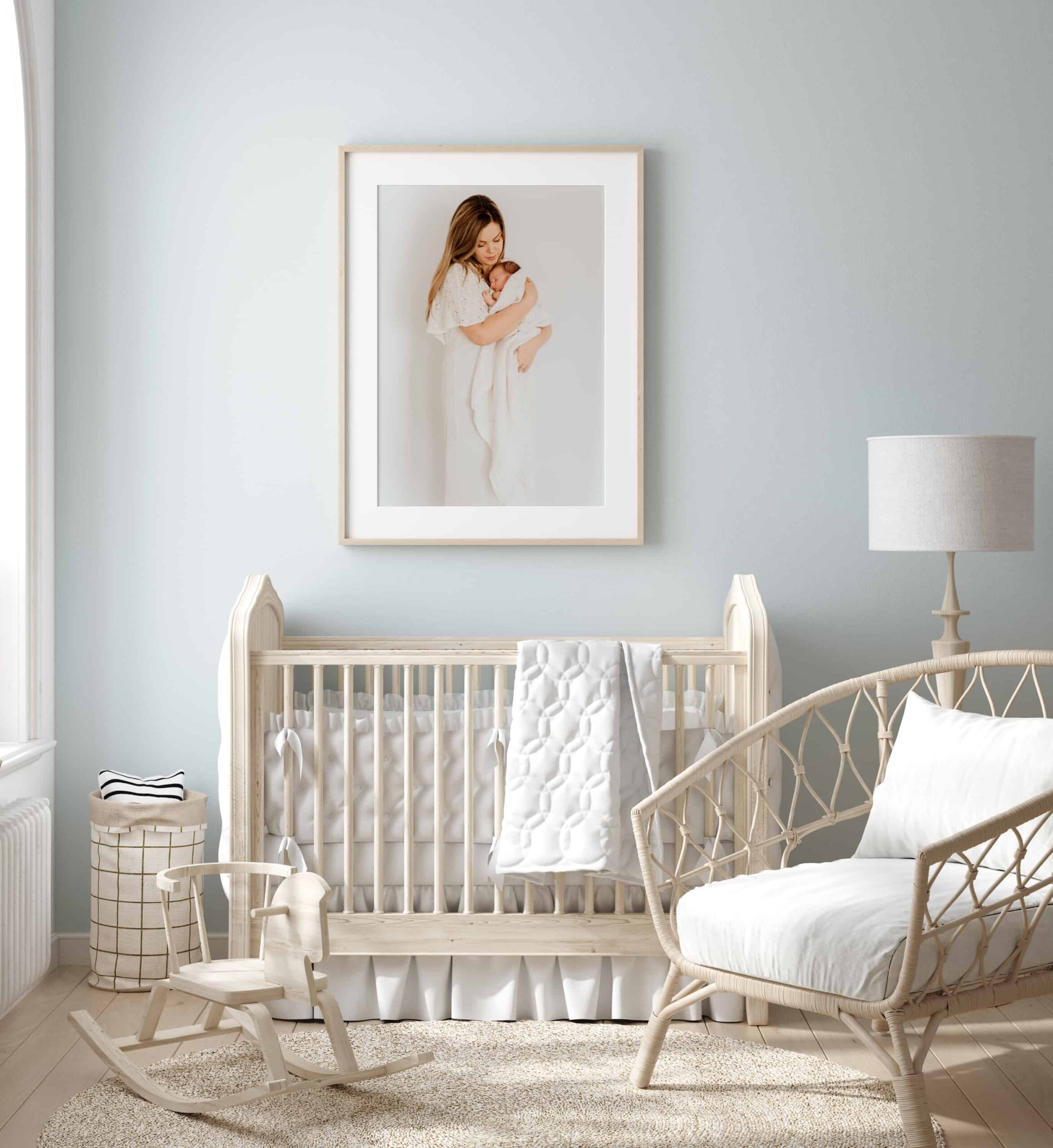 Interiør av et babyrom med et stort bilde fra nyfødtfotografering som henger over senga.
